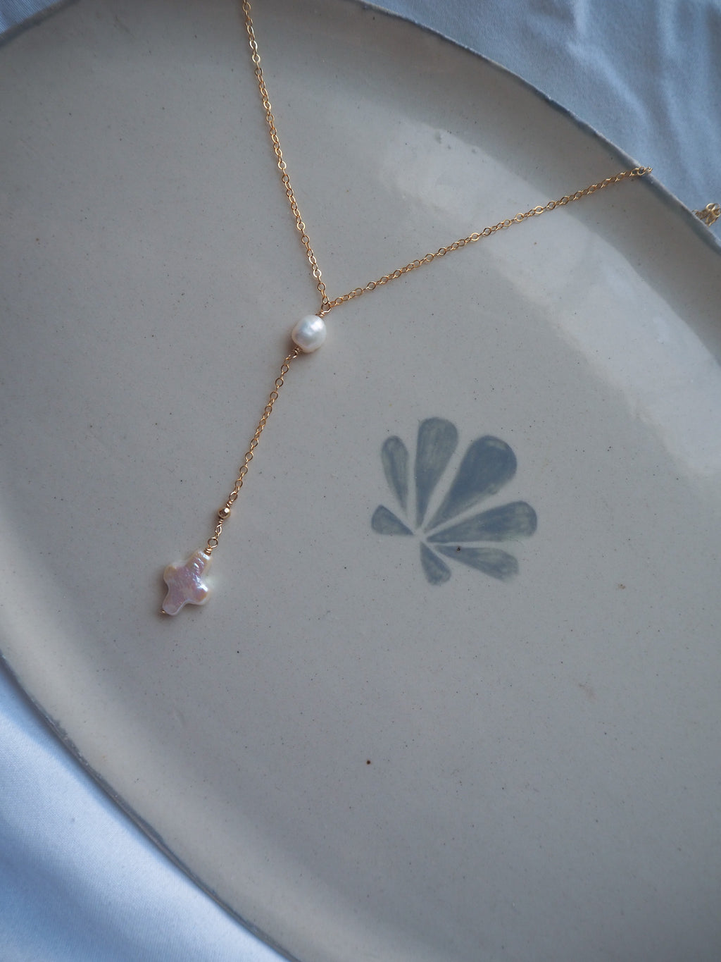 Minimal gold lariat pearl cross necklace flat lay with freshwater pearl and cross drop pendant, handmade coastal jewelry necklace