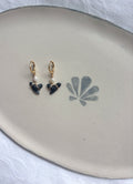 Gold shark tooth hoop earrings on plate flat lay