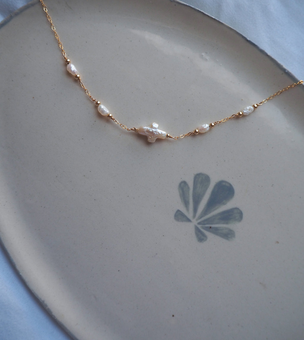 Dainty pearl cross necklace flat lay, handmade jewelry with freshwater pearls on gold chain, minimal coastal beach jewelry design