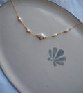 Dainty pearl cross necklace flat lay, handmade jewelry with freshwater pearls on gold chain, minimal coastal beach jewelry design