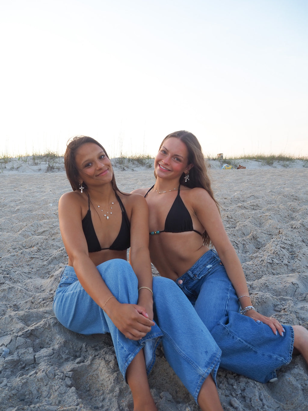 Women wearing layered pearl necklace and gold necklace on beach, handmade coastal jewelry styled for summer with pearl earrings